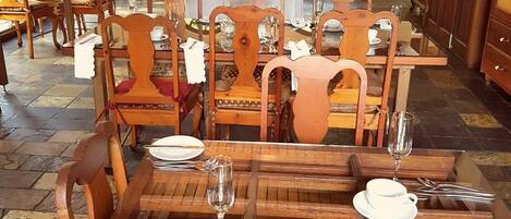 Un restaurante con mesas y sillas de madera, un candelabro y ventanas amplias.
