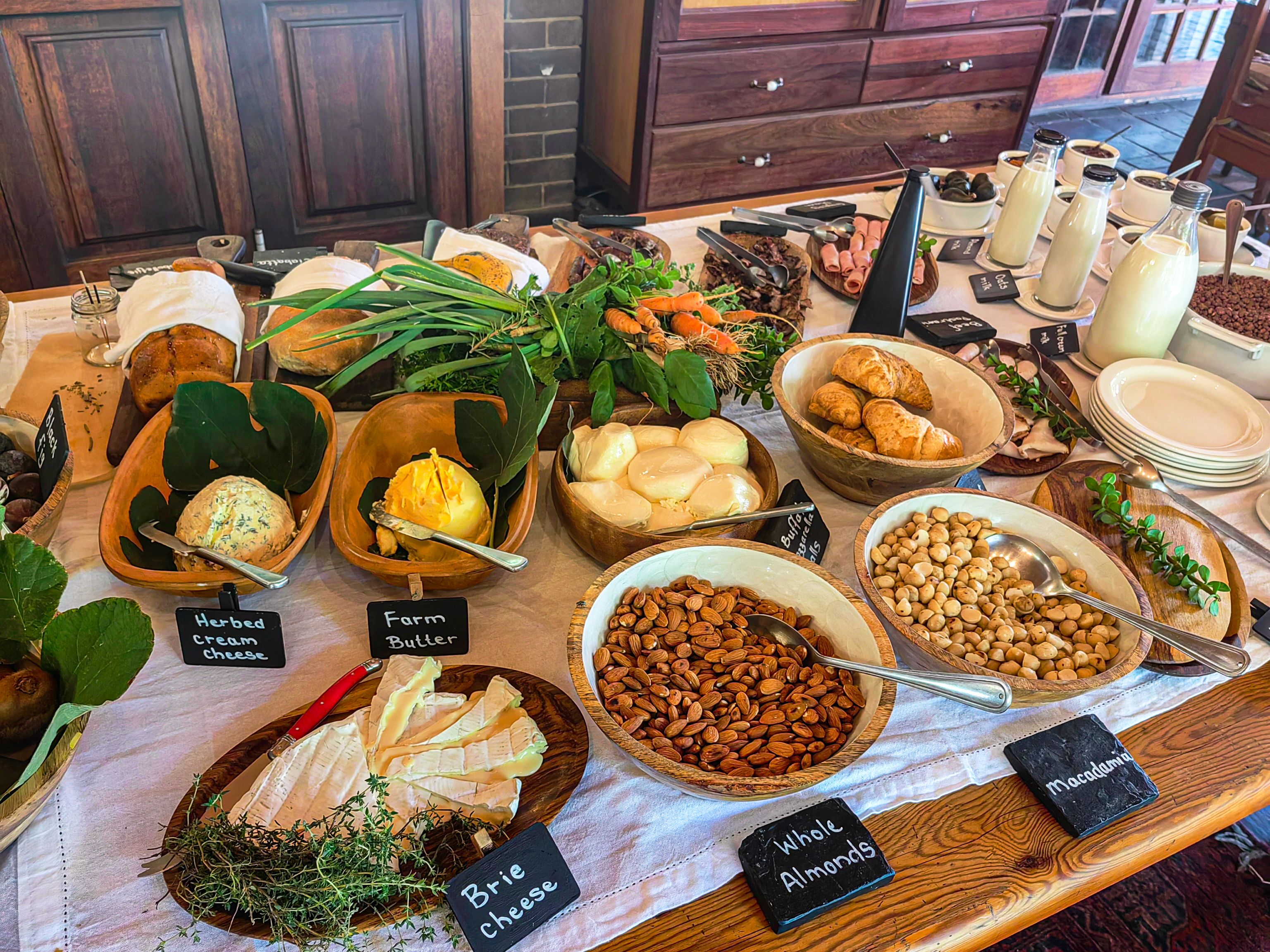 Una mesa de buffet con diversos alimentos, incluyendo queso, almendras y hierbas aromáticas.
