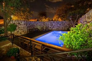 Una piscina al aire libre, sombrillas, sillones reclinables de piscina