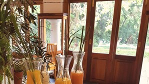 A wooden table with glass bottles and glasses, likely containing beverages, in a room with large windows and a view of greenery outside. - Kleinkaap Boutique Hotel (Centurion)