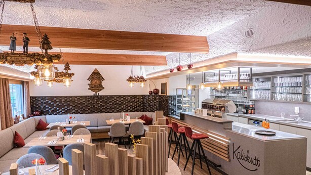 A modern restaurant interior with a bar area, wooden accents, and a stone wall backsplash. - Höhenhotel & Restaurant Kalikutt (Oppenau)