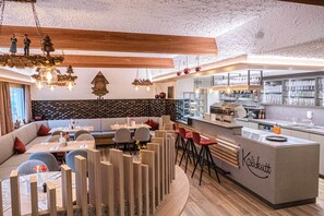 A modern restaurant interior with a bar area, wooden accents, and a stone wall backsplash. - Höhenhotel & Restaurant Kalikutt (Oppenau)