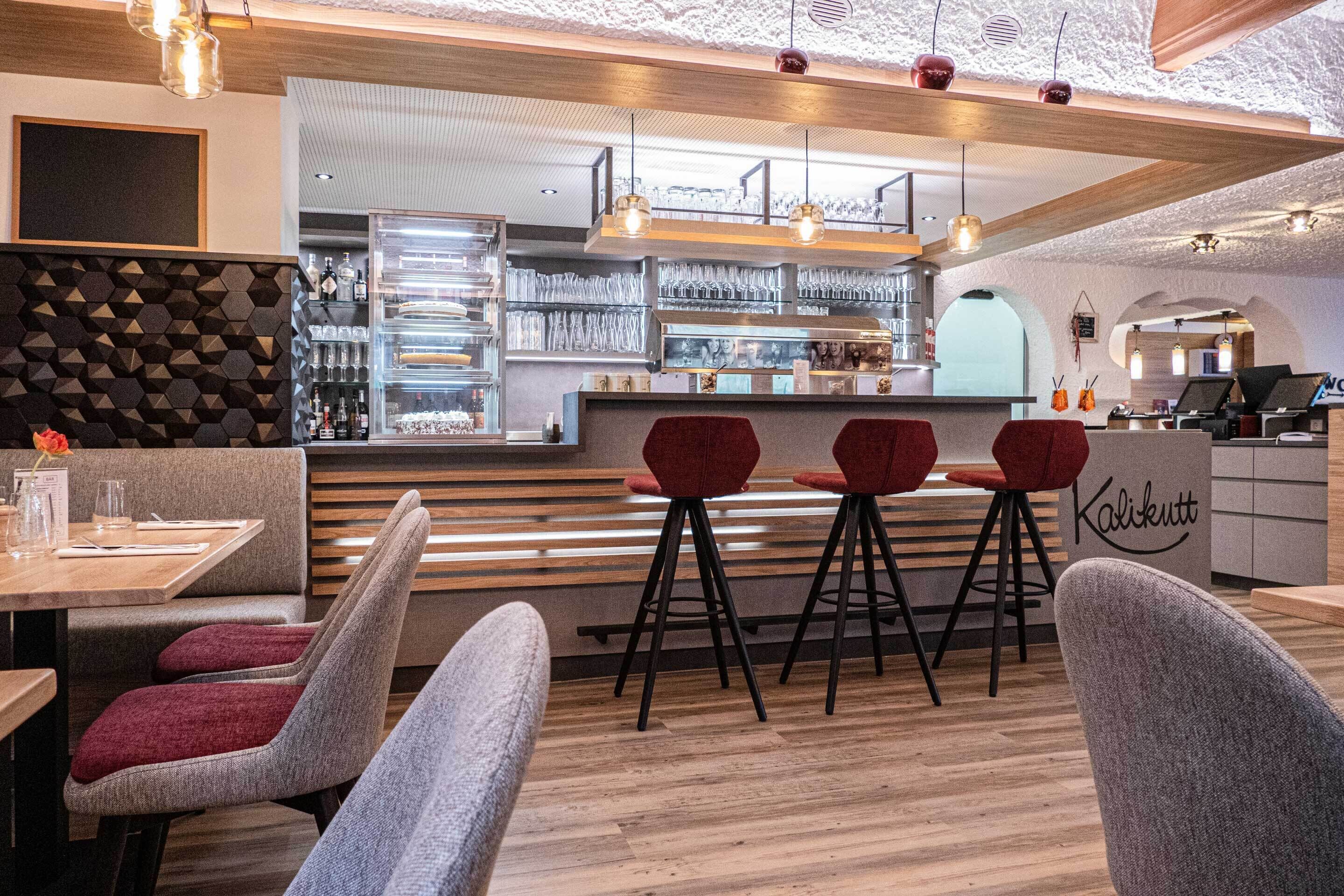 A modern bar area with a counter, stools, and a menu board.