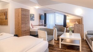 A modern hotel room with a large bed, two sofas, a small table, and a wooden wardrobe. - Höhenhotel & Restaurant Kalikutt (Oppenau)