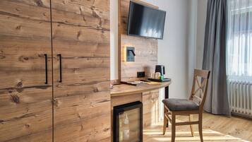 Ein modernes Zimmer mit Holzausstattung, einem Flachbildfernseher an der Wand, einem kleinen Tisch mit Stuhl und einer Heizung.