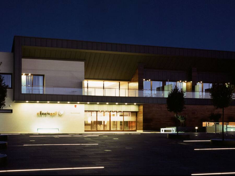 Un edificio moderno con techo plano, ventanas amplias y una entrada bien iluminada.
