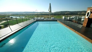 Piscina com deck de madeira, espreguiçadeiras e um colete salva-vidas.