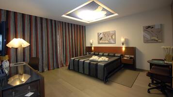 Una habitación de hotel moderna con una cama grande, un escritorio con lámpara, un televisor y obras de arte en las paredes.