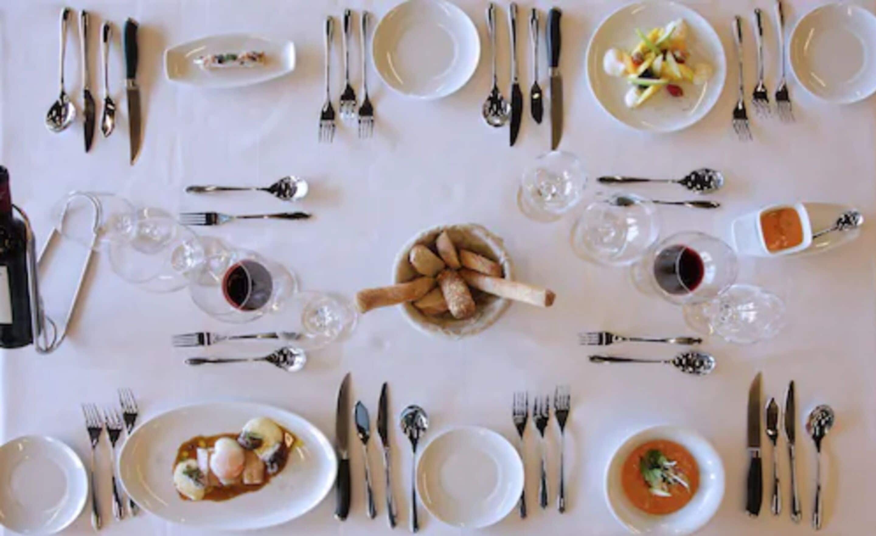 Una tavola da pranzo formale apparecchiata con piatti, posate e bicchieri, predisposta per un pasto.