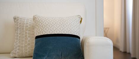 A white sofa with two pillows, one patterned and one solid blue.