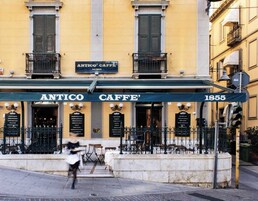 Un edificio con un letrero que dice "ANTICO CAFFE' 1855" y mesas y sillas para disfrutar del aire libre.