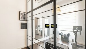 A modern interior with a glass partition, a treadmill, and exercise equipment.