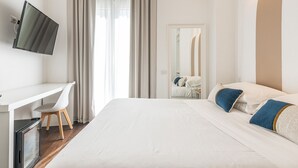 A hotel room with a bed, a desk, a chair, a television, and a mirror.