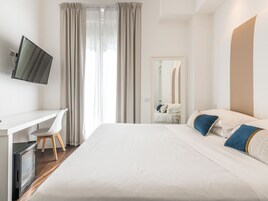 Una habitación de hotel con una cama, un escritorio, una silla, un televisor y un espejo.