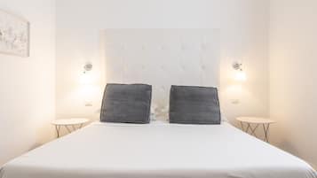 A neatly made bed with a tufted headboard, two bedside lamps, and a small round table.