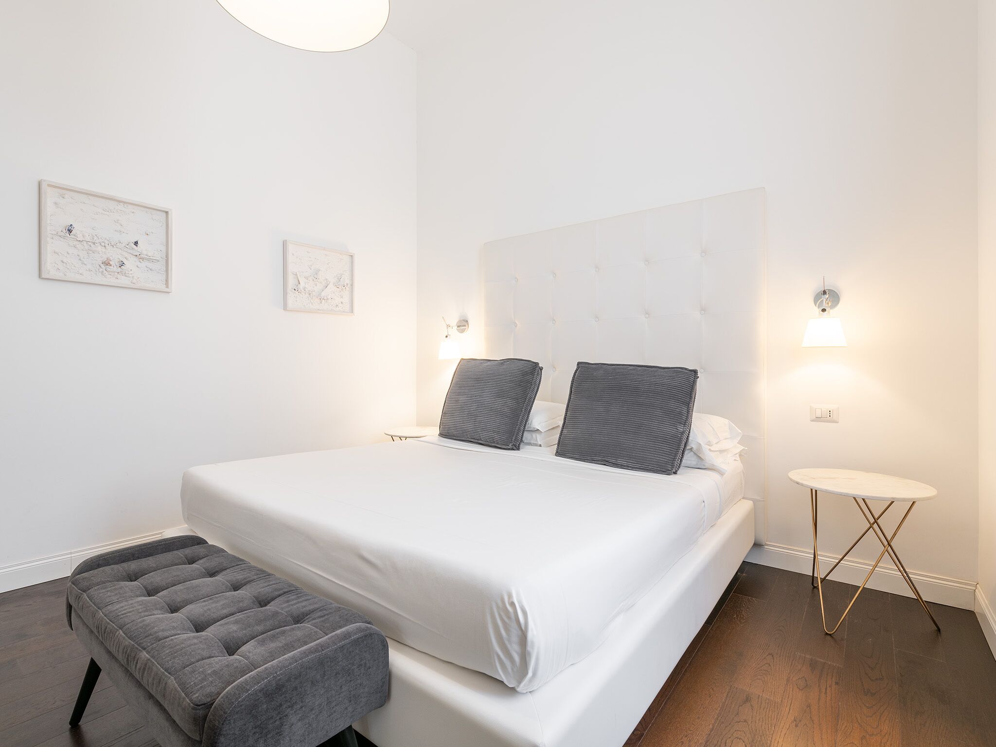 A neatly arranged bedroom with a large bed, a bedside table, a small round table, and a bench.