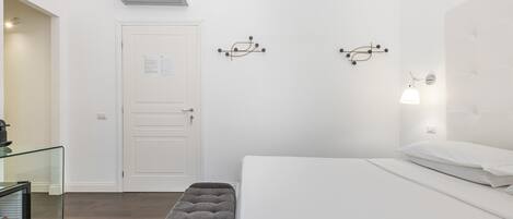 A minimalist hotel room with a bed, bench, and wall-mounted light fixtures.