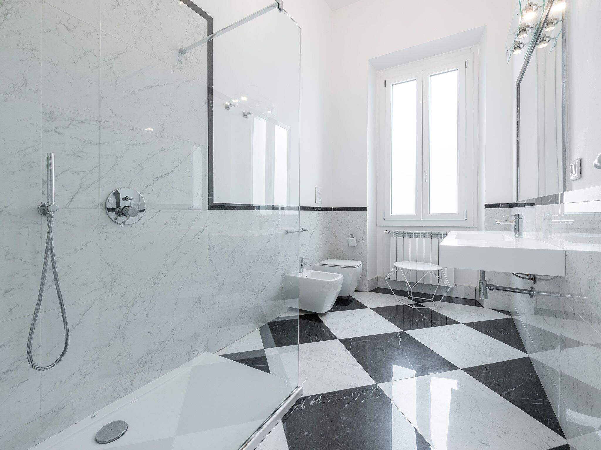 A modern bathroom with a checkered floor, a shower, a toilet, and a sink.