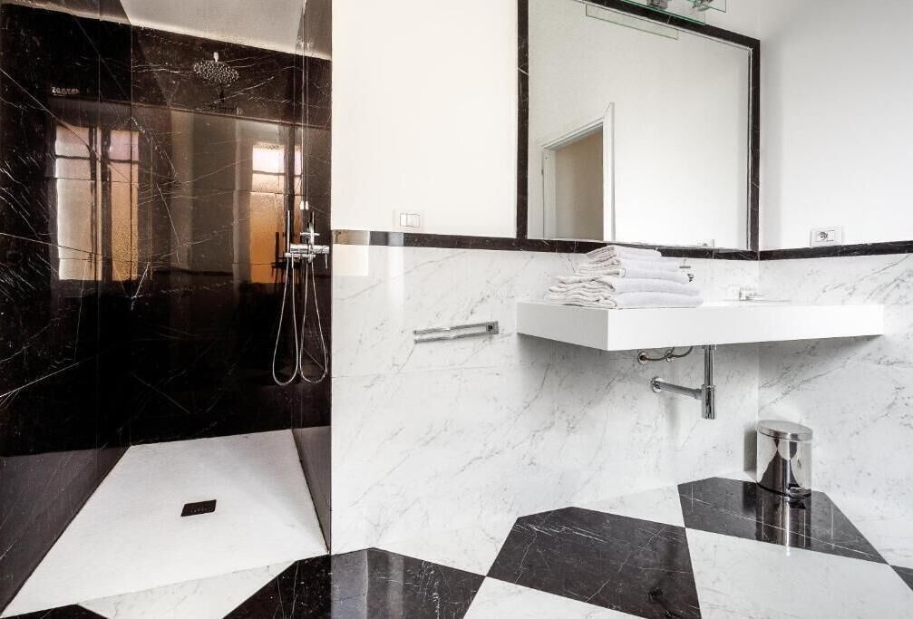 A modern bathroom with a black and white checkered floor, a white sink, and a large mirror above the sink.