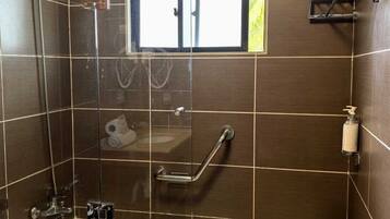 A bathroom with a glass-enclosed shower, a bathtub, a window, and a towel rack.