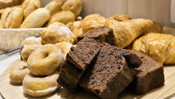 Variedad de productos horneados, incluyendo rosquillas, cruasanes y brownies, sobre una tabla de madera.