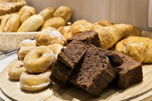 A variety of baked goods including donuts, croissants, and brownies on a wooden board. - Hotel Acta Laumon (Barcelona)