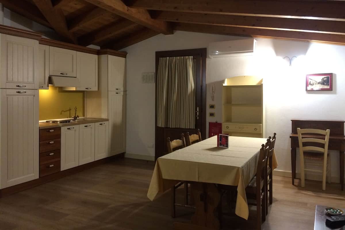 A compact kitchen with wooden cabinets, a dining table, and chairs.