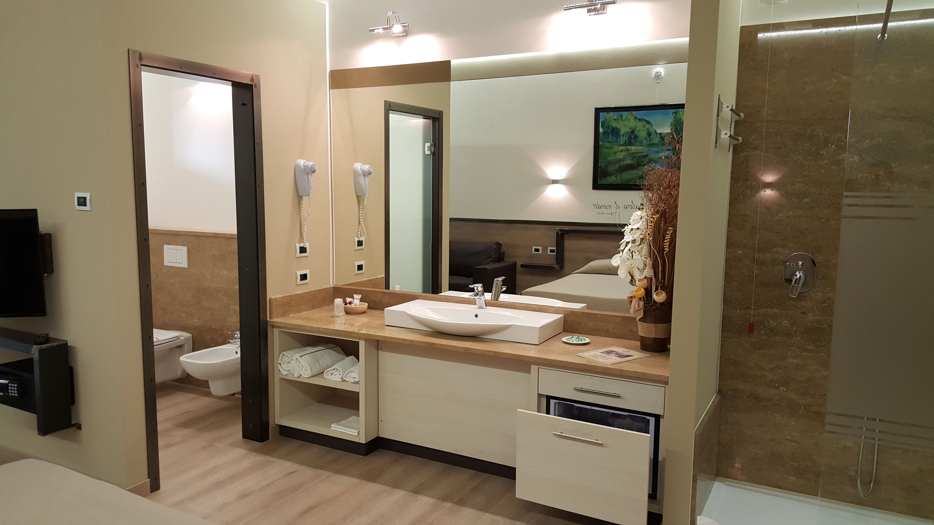 A modern bathroom with a large mirror, a sink, a toilet, and a shower.