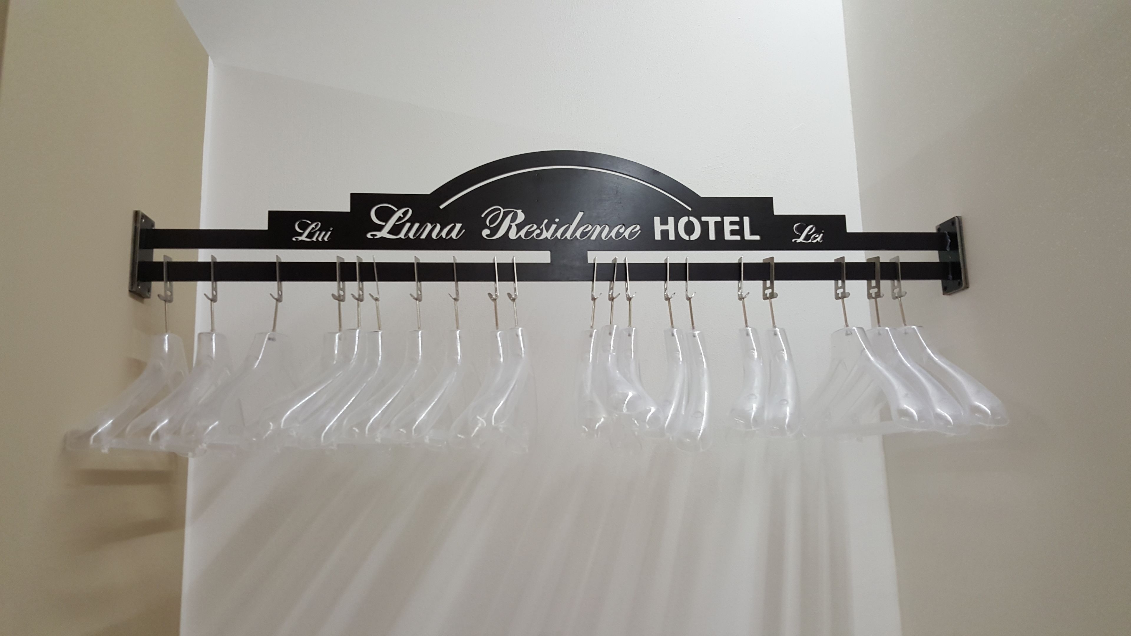 A hotel sign with the name 'Lui Residence Hotel' and a coat rack with several hangers.