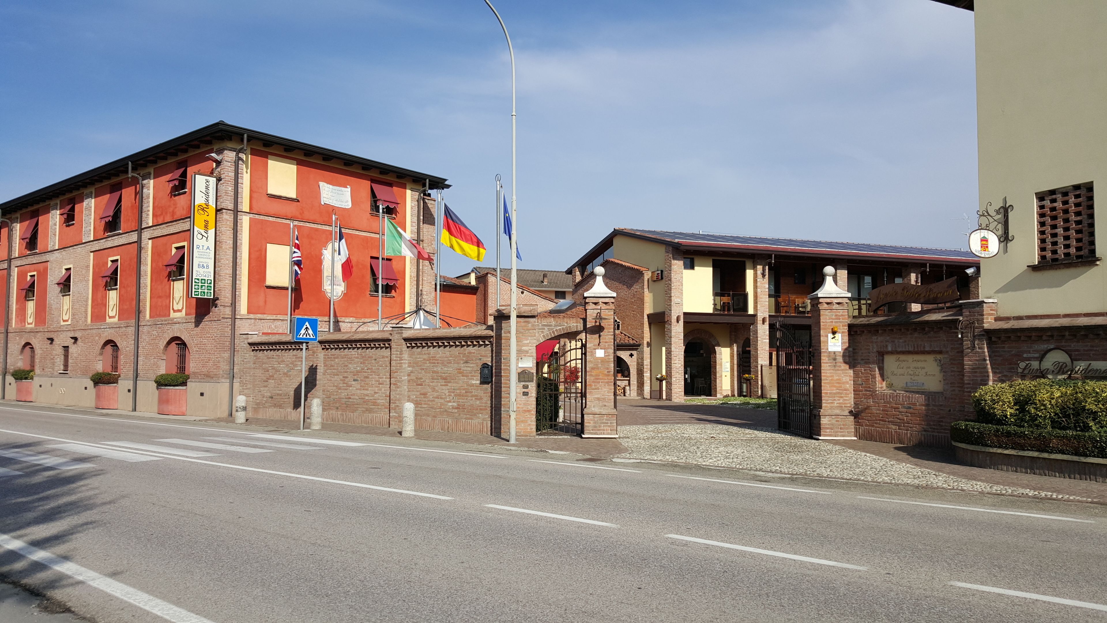 A building with a red facade, a gated entrance, and multiple flags.
