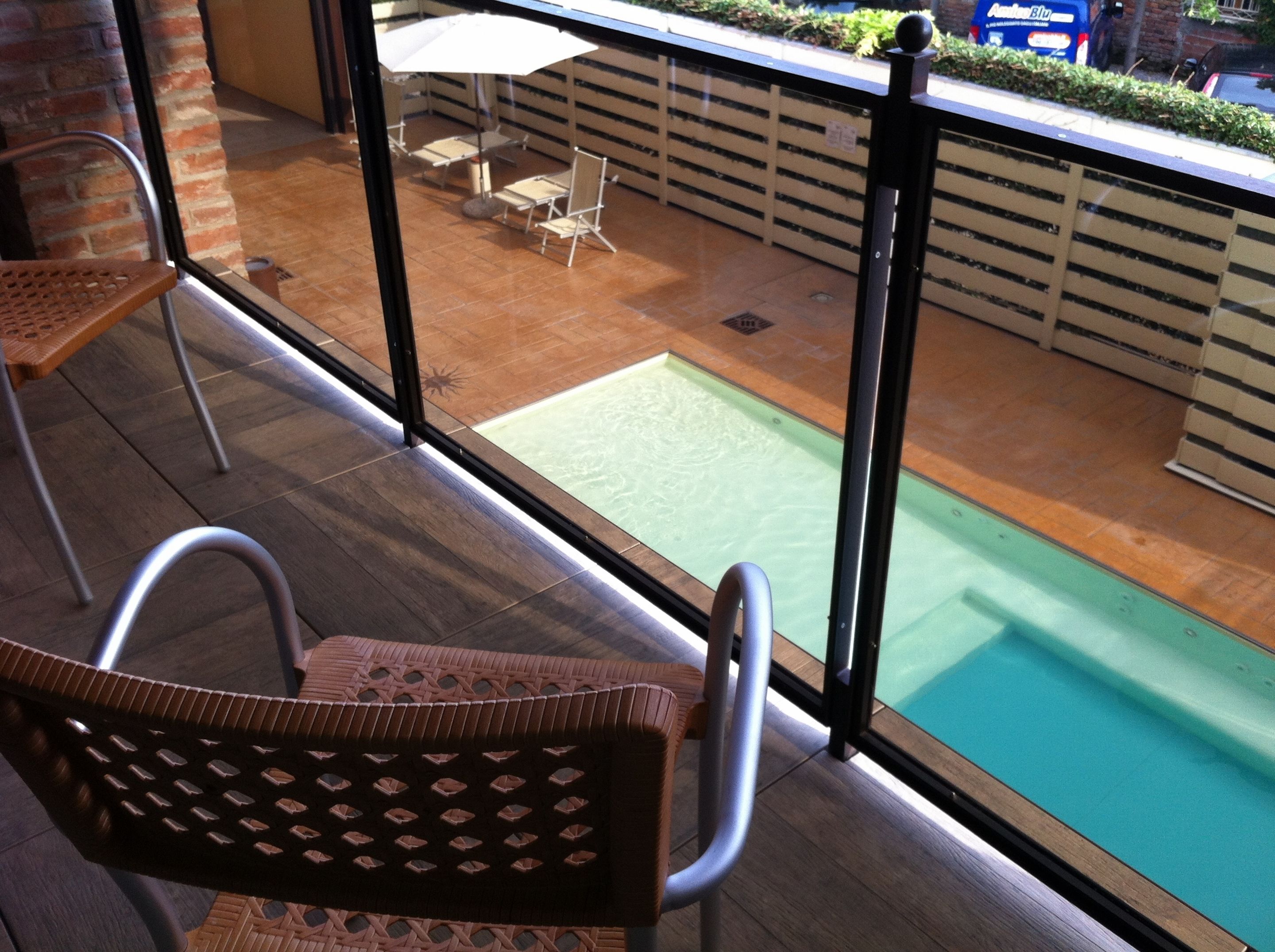 A balcony with a pool, chairs, and a view of the street.