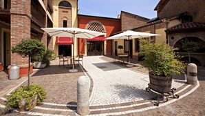 Un patio con piso de ladrillo, mobiliario exterior y plantas en macetas.