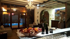 Un interior moderno con vista a la piscina, un candelabro y una zona de bar con botellas de vino y copas.