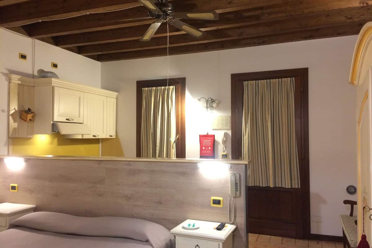 A bedroom with a bed, bedside table, nightstand, and a ceiling fan.