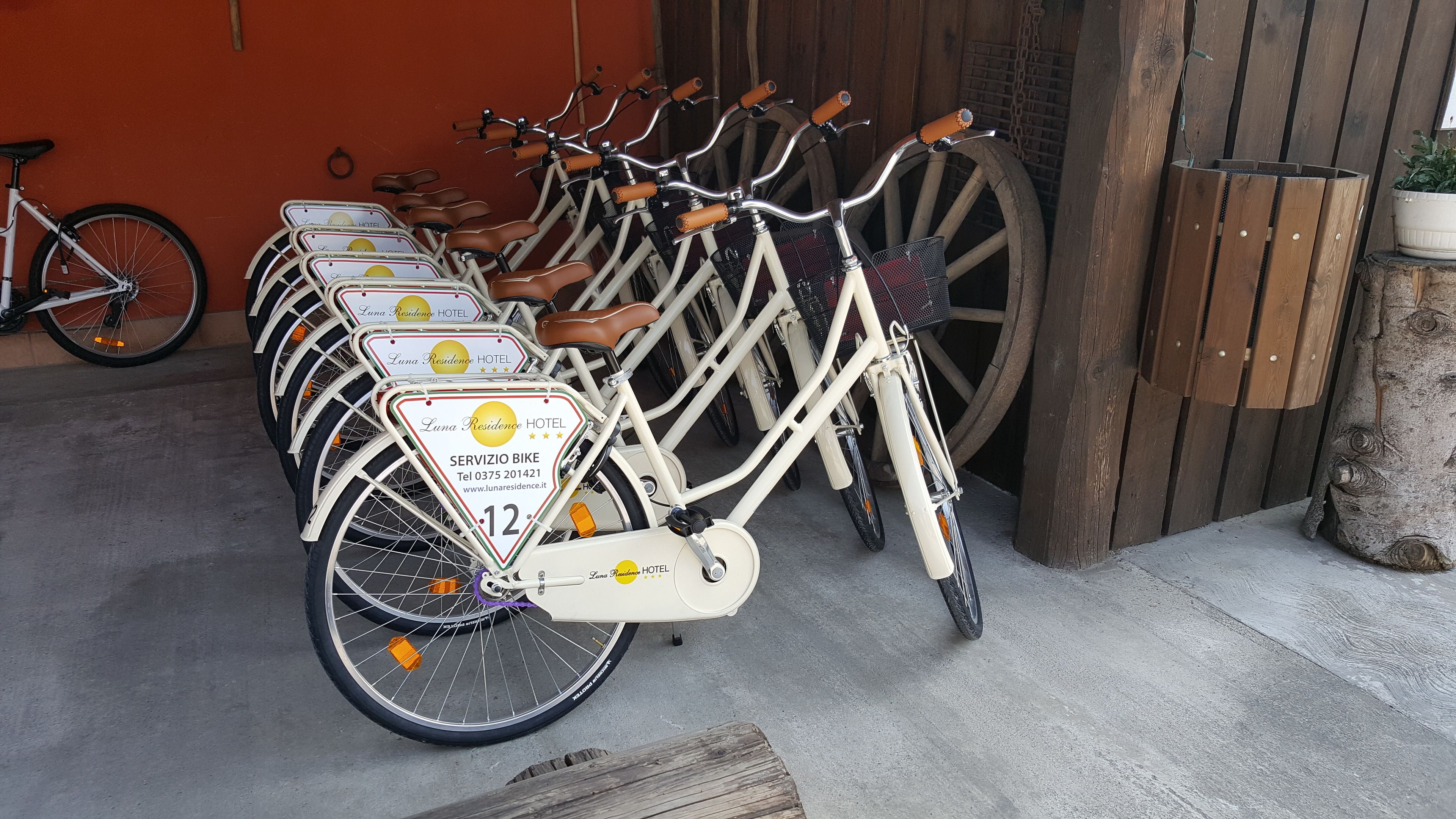 A row of bicycles with branded signage, a wooden wheel, and a rustic setting.