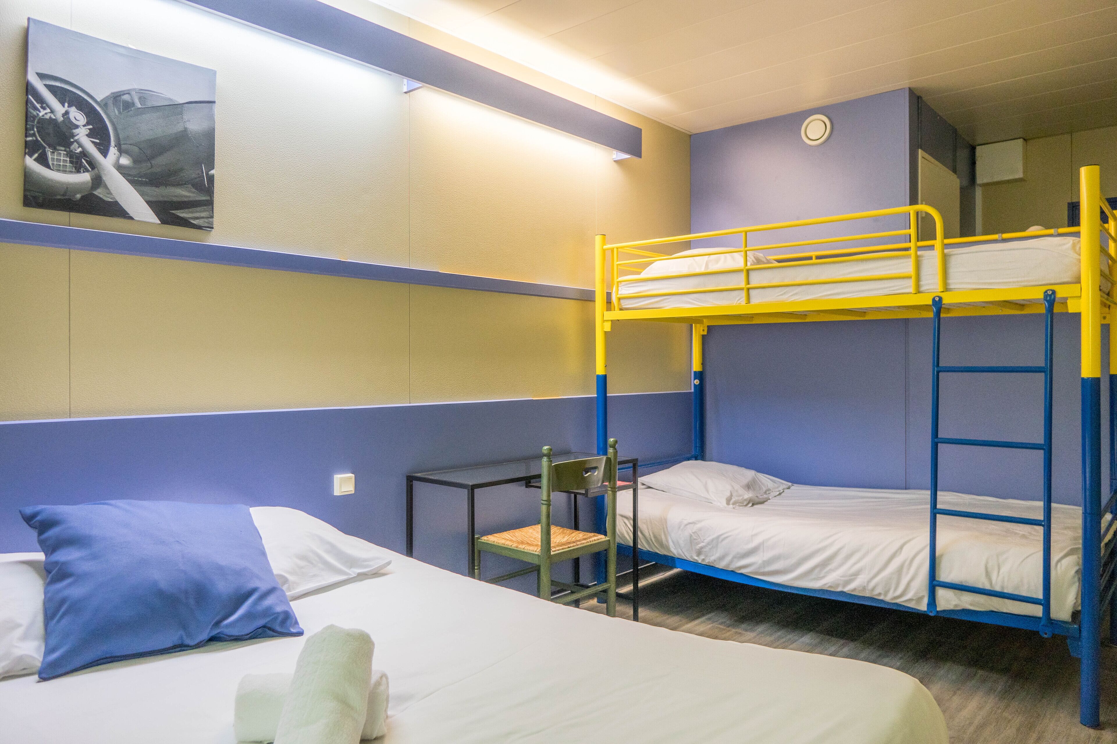 A bunk bed room with a single bed, a chair, and a wall-mounted shelf.