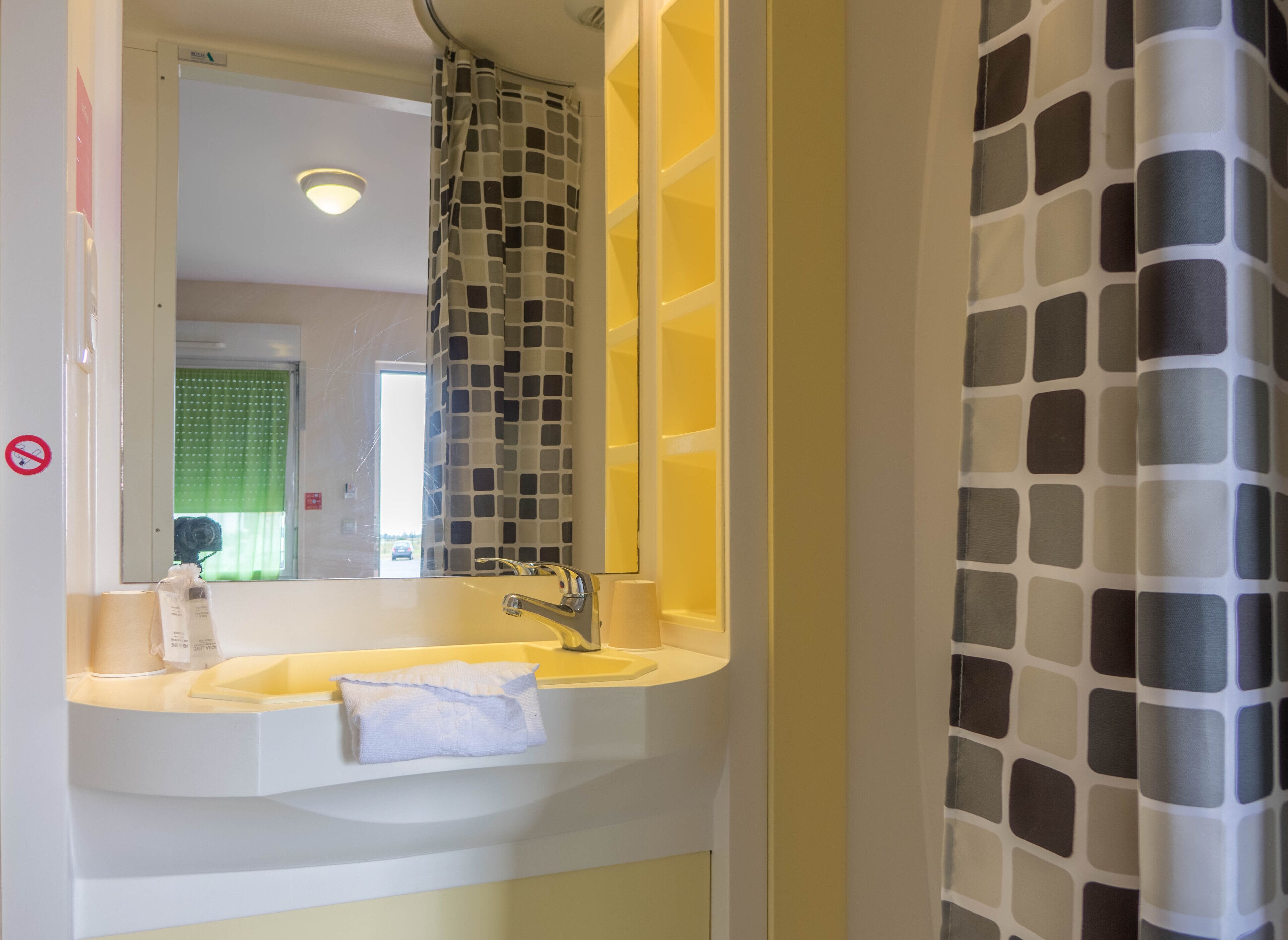 A bathroom with a sink, mirror, and shower curtain.