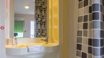 A bathroom with a sink, mirror, and shower curtain.