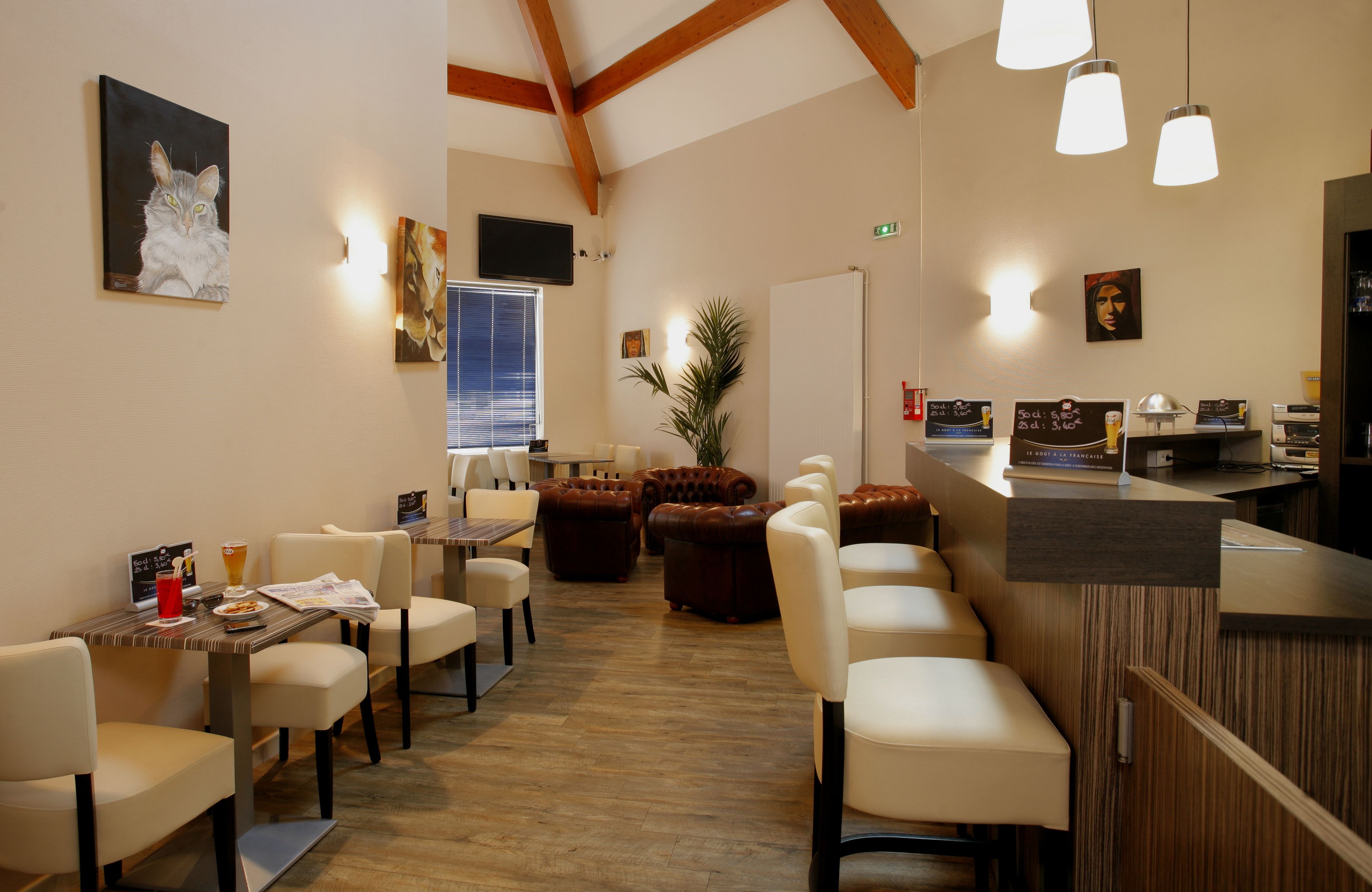A restaurant with wooden beams, pendant lighting, and a bar area.