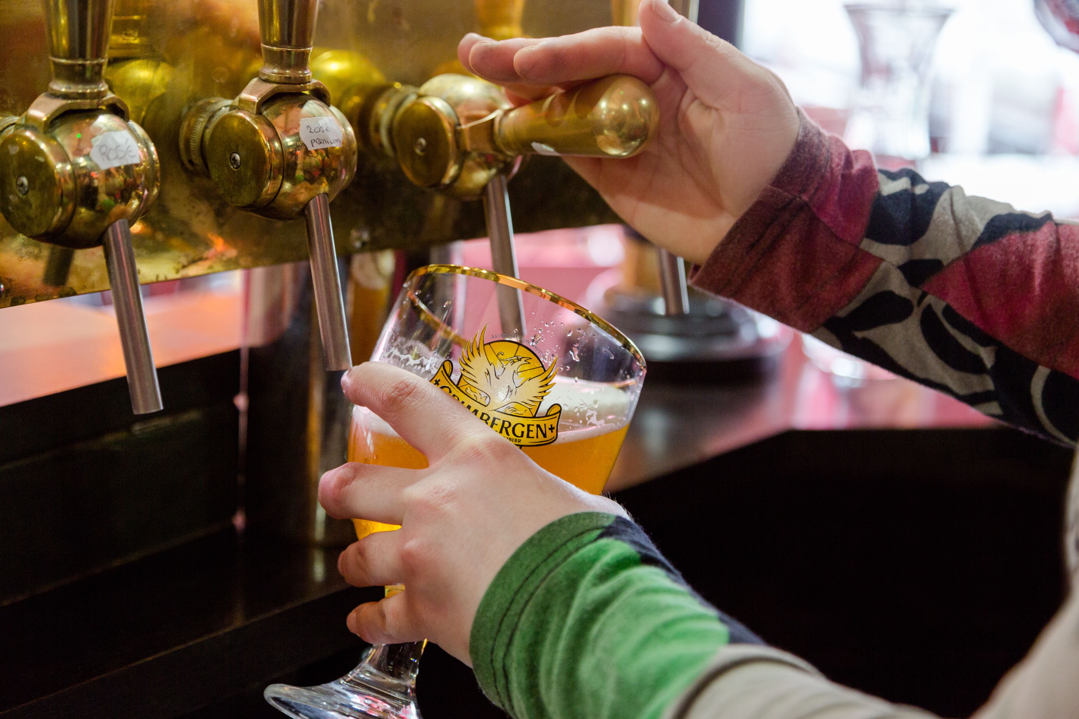 Iemand giet bier in een glas met een logo.