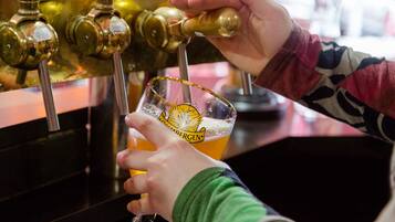 Iemand giet bier in een glas met een logo.