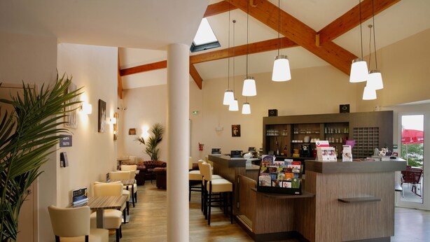 A hotel lobby with a reception desk, seating area, and wooden beams on the ceiling.