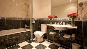 A bathroom with a bathtub, toilet, and sink, featuring a checkered floor and a large mirror. - Logis Hôtel les Hauts de St Maure (Sainte-Maure-de-Touraine)
