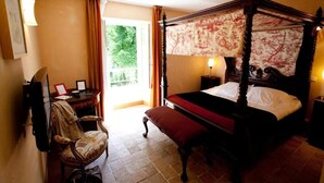 A four-poster bed with a canopy, a desk with a chair, and a television. - Logis Hôtel les Hauts de St Maure (Sainte-Maure-de-Touraine)