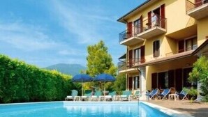 Um hotel com piscina, área de estar externa e montanhas ao fundo.