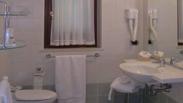 A bathroom with a toilet, bidet, sink, and bathtub. There is a window with curtains, a towel rack, and a mirror.