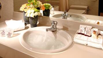 A bathroom with a sink, mirror, and toiletries.
