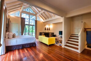 A bedroom with a bed, a yellow sofa, a fireplace, and a staircase. - Sutera Sanctuary Lodges at Kinabalu Park (Ranau)
