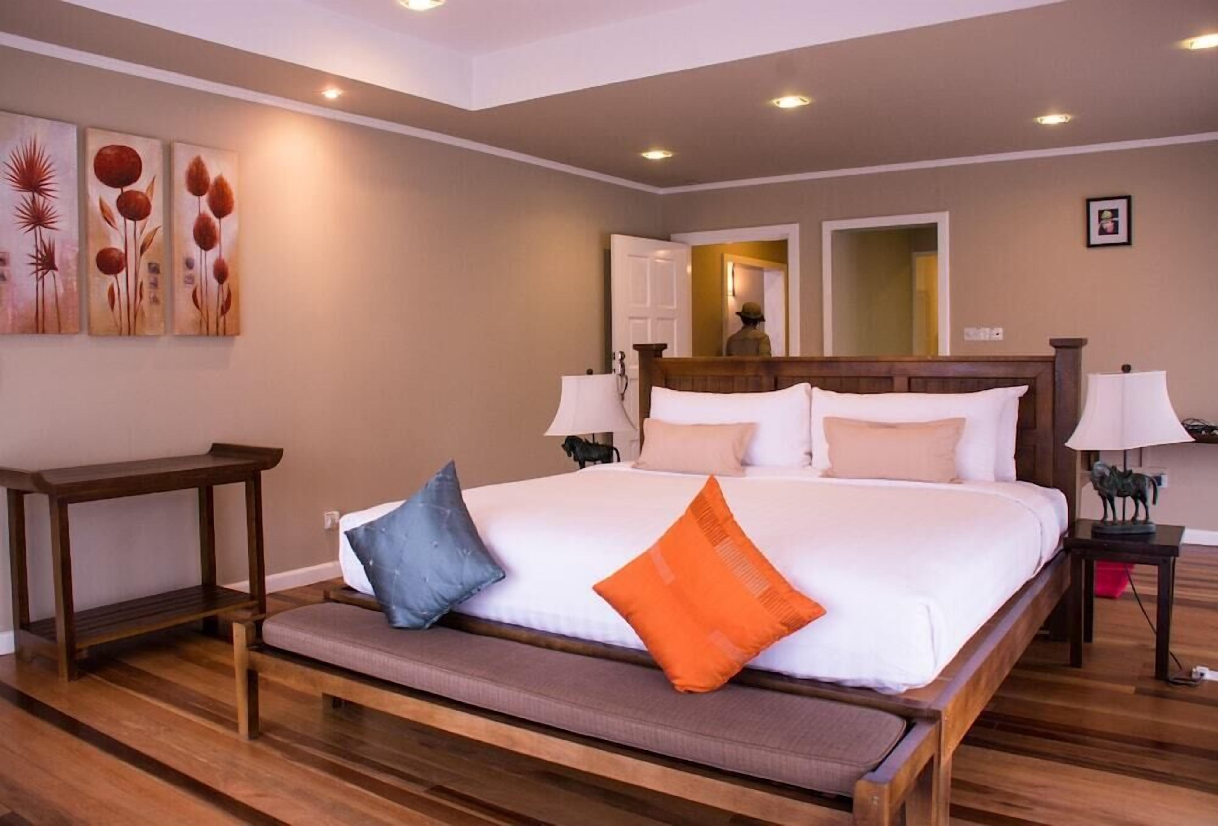 A spacious bedroom with a large bed, a bench, and a nightstand.