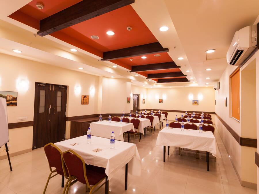 Un salón de conferencias con varias mesas, sillas y una pizarra.